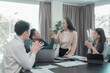 © ArLawKa - Group of successful Asian businesspeople smiling and laughing, posing and making gestures of joy together in a company office conference room.