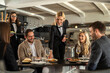 © Creative Light - Restaurant staff serving food to a group of happy customers at a table