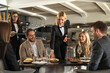 © Creative Light - Restaurant waiter serving food to happy customers at a dining table