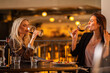 © Creative Light - Two women enjoying red wine at a restaurant, celebrating a special occasion