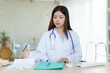 © DG PhotoStock - Asian female doctor working on medical report documents.