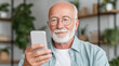 © Katerina Bond - Smiling senior man with glasses using smartphone at home, enjoying technology and communication in a relaxed, modern indoor setting with soft natural light.