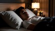 © photostockatinat - A man resting peacefully in bed, bedroom interior, night shot with lamp lighting. The man is asleep and relaxed