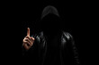 © Alejandro Bernal - a faceless hooded man in the shadows pointing to the sky with his right hand and a black background