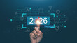 © krungchingpixs - Concept of 2026 business trends. Finger touching at target of 2026 and digital interface with icons of AI, finance, e-commerce, innovation and data analytics. Transformation and global progress.