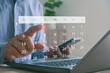 © MUNTHITA - Businessman using laptop and smartphone touching digital calendar interface, selecting date for scheduling, event planning or time management in modern online productivity applications.