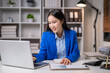 © Wasana - Businesswoman analyzing data on laptop in office