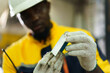 © DG PhotoStock - African engineer inspecting metal part from machine for quality and precision.