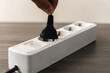 © panadesignteam - White Power Strip with Black Plug Being Unplugged by a Hand
