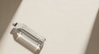 © Rani - A clear plastic water bottle lies on a neutral beige surface, cast in bright, direct sunlight creating a strong diagonal shadow.