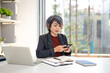 © Fahng - Busy middle aged 50s business woman holding cell mobile phone using cellphone in corporate office. Smiling mature businesswoman executive manager professional businesswoman working on smartphone.