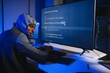 © Serhii - African american Hacker with computer, man sitting at a table in a hoody