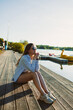 © DSMT - Young woman relaxing by the lake as the sun sets, enjoying the peace of nature and contemplating life on a wooden pier