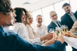 © deagreez - Group of diverse coworkers celebrating success in office setting with champagne toasts, showcasing teamwork and professional achievement