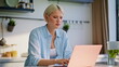 © stockbusters - Serious copywriter typing computer sitting at apartment kitchen desk closeup