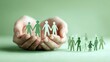 © Yuliia - Hands holding paper cutout family figures against green background, symbolizing care, protection, and community support for social services and family welfare programs.