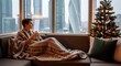 © Wool World - Cozy winter morning A woman sips a warm drink by the window, enjoying the festive Christmas tree and modern city skyline view