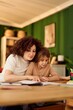 © bnenin - Mom Helps Daughter Do Homework Together At The Kitchen Table In Cozy Home