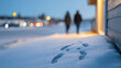 © perfectlab - Footprints in fresh snow near a building with two blurred figures walking in the background during twilight with soft bokeh lights