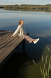 © Anna - happy young European woman in her twenties enjoys relaxing outdoors on a wooden pier on a sunny day. She loves life, well-being, and a positive attitude. A long-awaited vacation.