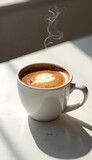 Cup of cappuccino with latte art on white background in natural sunlight
