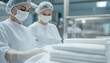 © photo for everything - Two healthcare workers in sterile attire folding clean linens in a medical facility. Focused on hygiene and infection control, ensuring patient safety with meticulous linen management.