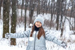 © Nataliia - Joyful girl in a silver winter coat playing in the snow in a forest park