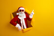 © deagreez - Charismatic Santa Claus pointing on a yellow background, expressing festive cheer and promoting joyful holiday celebration