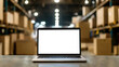 © photo for everything - Open laptop in warehouse, blank screen ready for content insertion. Boxes on shelves blurred in background, focus on screen & modern keyboard. Online logistics concept.