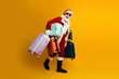 © deagreez - Santa Claus carries multiple colorful suitcases on a vibrant yellow background, symbolizing holiday travel and festive cheer