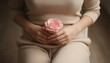 © SERHII - A woman in beige loungewear holds a pink rose over her abdomen. Women's health, menstruation, menopause and self-care concept