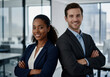 © Gianpiero - Confident corporate portrait of two smiling business professionals, a man and a woman, standing back to back with arms crossed in a modern office environment