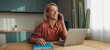 © FATNA - png Smiling blonde woman talking on the phone while working on a laptop at home enjoying a relaxed and productive day