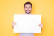 © Volodymyr - Banner blank board concept. Happy man holds the sign, blank card placard. Sign to your text. Smiling man showing blank sign board over studio background. Empty blank board. Copy space advertising.