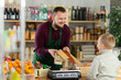 © JackF - Friendly middle-aged salesman offering turrons to little boy in grocery store