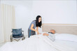 © Creativa Images - Happy Caregiver Smiling at Content Elderly Man Tucked into Bed at Home