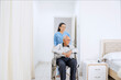 © Creativa Images - Smiling Nurse Pushing Elderly Male Patient in Wheelchair in a Hospital or Home Setting