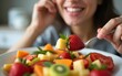 © Margaret - Close-up of woman eating fruit salad in the kitchen. High quality