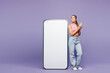 © ViDi Studio - Full body young smiling woman wear pink tank top casual clothes big huge blank screen mobile cell phone with area using smartphone isolated on plain pastel light purple background. Lifestyle concept.