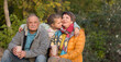 © ulza - Little child girl hugs grandpa and grandmother On Walk iin nature on a sunny autumn day. Concept of friendly family.