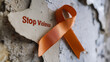 © A2Z AI  - An orange ribbon symbolizes the collective effort to raise awareness about the urgent need to prevent violence. It is positioned next to a written 'Stop Violence' poster.