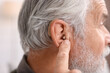 © New Africa - Senior man with hearing aid at home, closeup