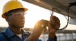 © Habiba - Closeup of an electrician wearing a yellow hard hat and safety glasses, carefully connecting wires on a solar panel installation during the day