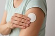 © Tanakorn - Female applies discreet round hormone patch to upper arm, demonstrating proactive self-care for wellness, health, and hormone balance