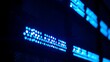 © Mio - Close-up of glowing blue server rack lights creating an abstract technological pattern on a dark background.