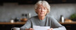 © SolaruS - A thoughtful senior woman reviews paperwork at her kitchen table. Captures reflection, aging, concern, financial planning, and document review. Use for insurance, retirement, or care concepts.