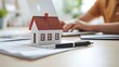 © Abdul - Dreaming of owning a home? Researching mortgage rates and property values online with a miniature house model on the desk for inspiration