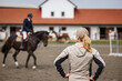© encierro - Female horse trainer supervising rider training before equestrian show jumping in paddock