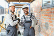 © Serhii - Builders shaking hands at construction site celebrating successful masonry work