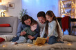 © New Africa - Happy family with open magic Christmas gift on floor in festive decorated room